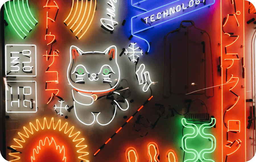 Colorful neon signs including a waving cat, Japanese characters, and the word 'TECHNOLOGY' against a dark background.